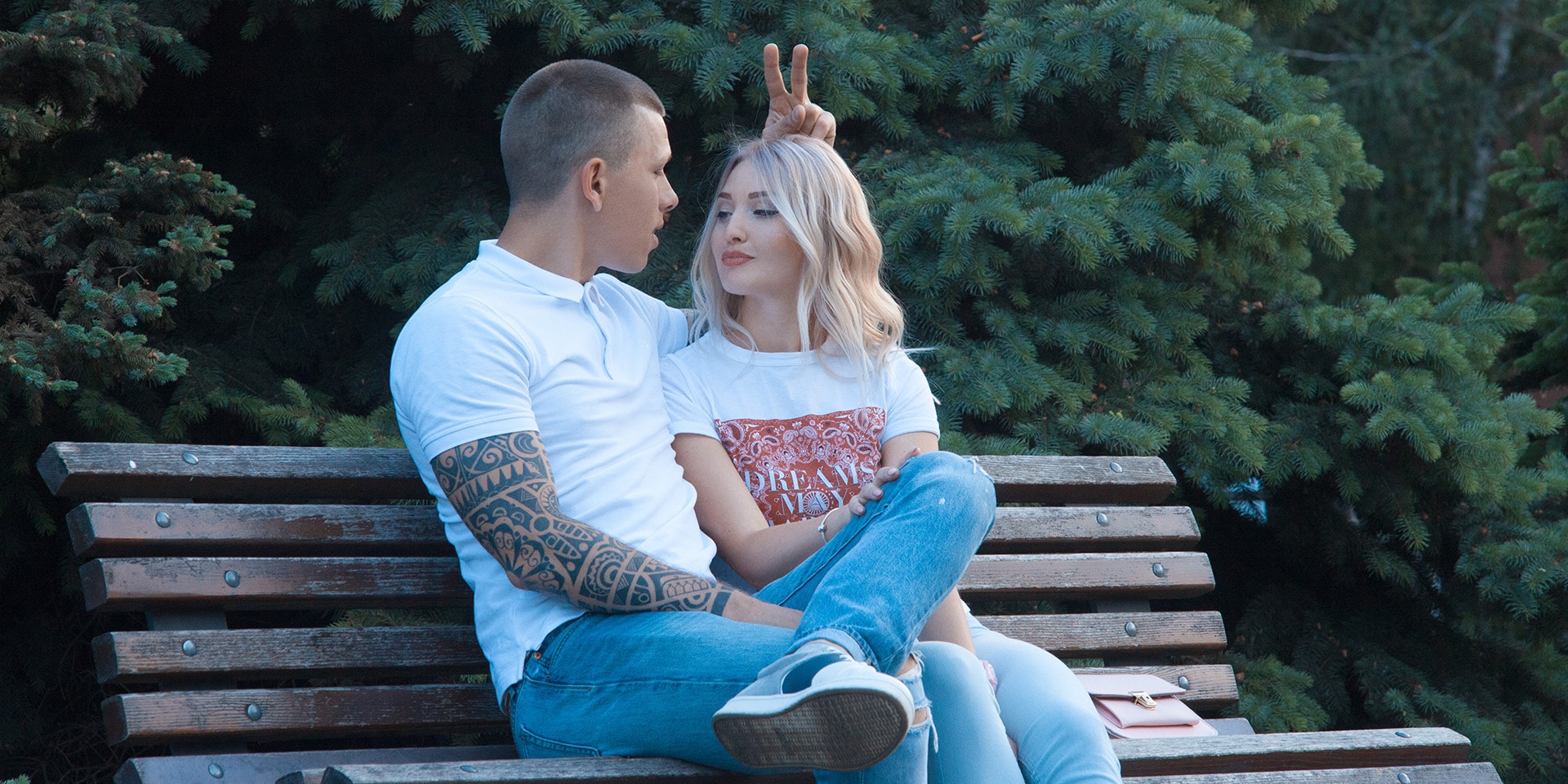 A girl with a guy on a bench in the park watching the phone